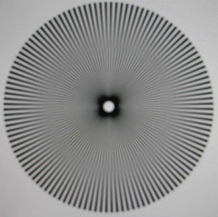 The same star segment target from figure 1.3.1 photographed from a LCD monitor and purposely defocused. Note the ring-shaped areas of minimal contrast (nodal points) , spurious resolution and contrast reversal. (after (Smith 1982))